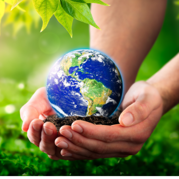 Two hands holding soil with a glowing earth resting atop the soil, greenery in the background