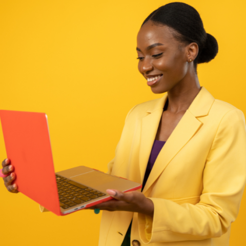 Women holding a laptop, smiling at the screen.