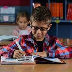 A boy uses the C-Pen Reader 2 with earbuds
