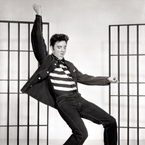 Black and white photo of Elvis up on his toes arm thrown up in the air