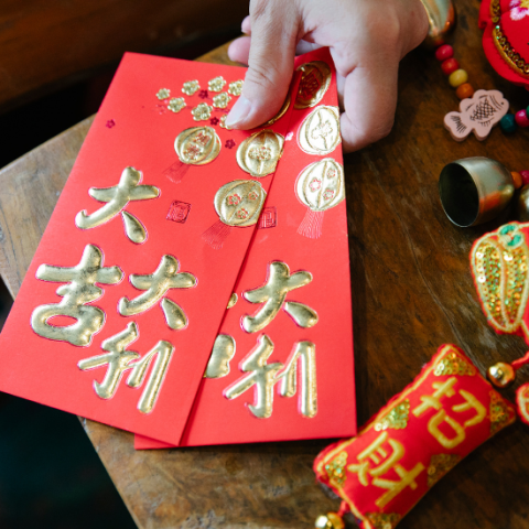 Hand holding two red Chinese New Year envelopes 